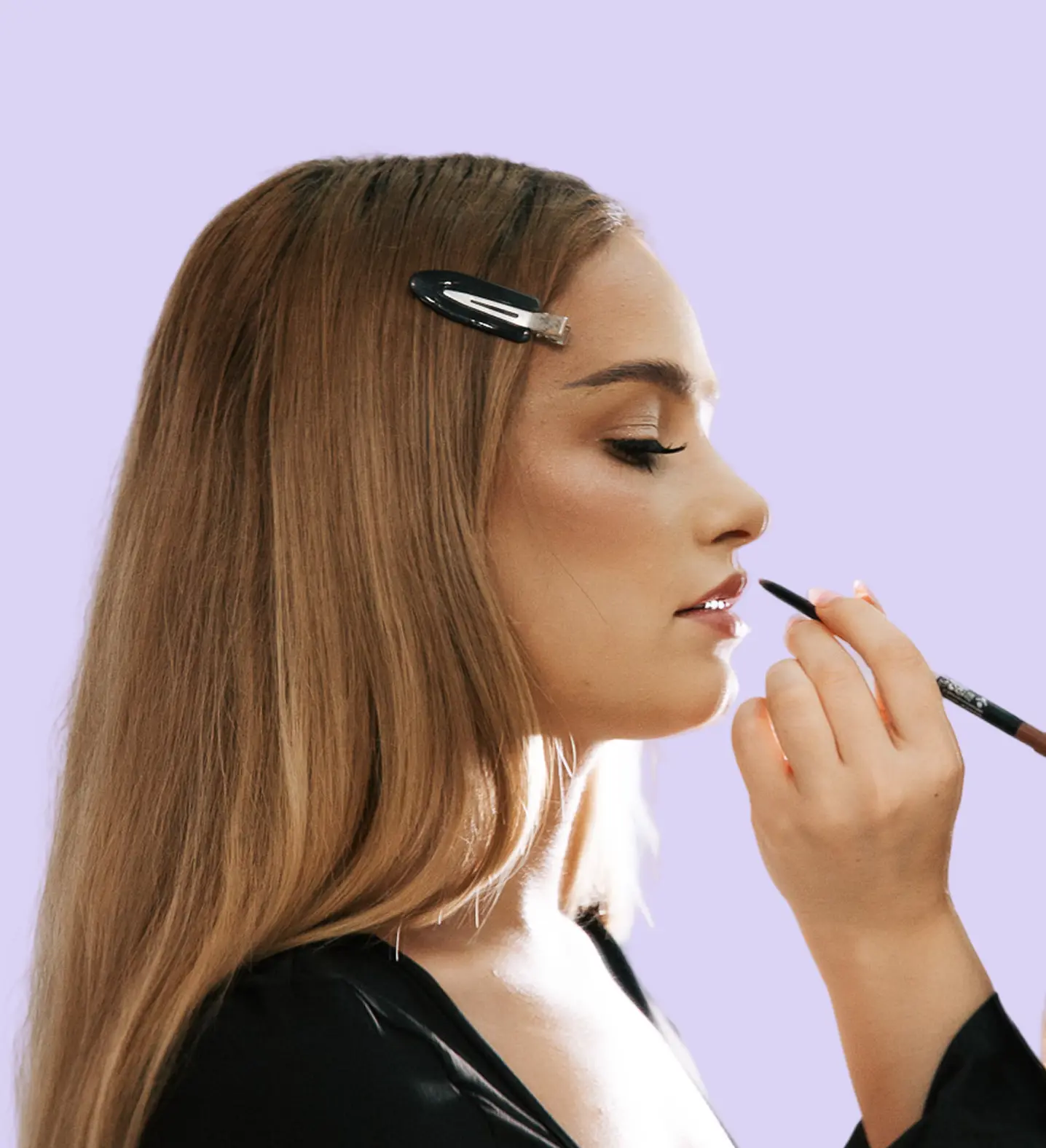 Makeup artist conturează forma buzelor unui model, compoziție ce arată serviciul de makeup